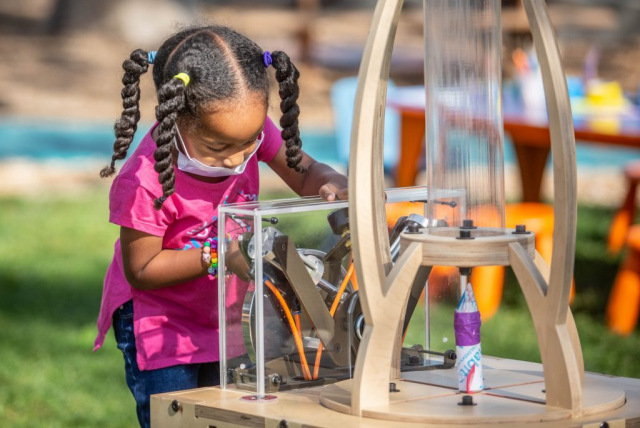 Child turning a crank to build pressure to launch a tp tube rocket